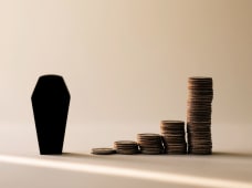 Un cercueil noir &agrave; c&ocirc;t&eacute; de piles de pi&egrave;ces.
