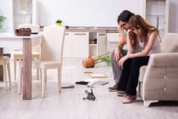 Un homme et une femme assis sur le canap&eacute; apr&egrave;s avoir retrouvant leur maison cambriol&eacute;e.