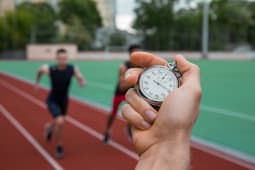 Main chronom&egrave;tre, deux coureurs sur une piste d?athl&eacute;tisme.