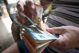 Une personne compte des billets de banque en euros.