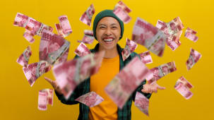 Un homme joyeux en bonnet et en v&ecirc;tements d&eacute;contract&eacute;s avec des billets de banque volant dans l'air.