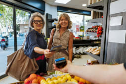 Deux femmes paient des courses avec un t&eacute;l&eacute;phone dans magasin.