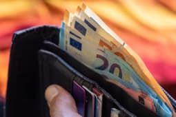Portefeuille noir rempli de billets en euros et de cartes de cr&eacute;dit tenu &agrave; la main
