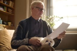 Un homme &acirc;g&eacute; lit un document tout en &eacute;tant assis avec son chien de compagnie.