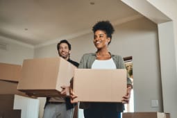 Couple heureux, immobilier et emm&eacute;nagement avec des cartons pour r&eacute;novation, investissement ou r&eacute;installation dans une nouvelle maison. Homme et femme interraciaux, propri&eacute;taire agent immobilier, portant une bo&icirc;te dans la maison, d&eacute;m&eacute;nagement ou pr&ecirc;t immobilier ensemble.