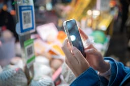 Personne utilisant un smartphone pour le paiement par QR code dans un march&eacute; de rue alimentaire urbain la nuit