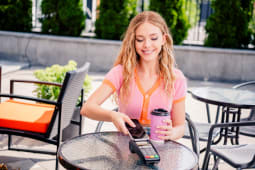 Portrait d'une charmante fille positive buvant du caf&eacute; le matin, le week-end, paiement sans esp&egrave;ces au caf&eacute; restaurant &agrave; l'ext&eacute;rieur