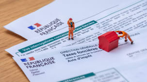 Clamart, France - 6 septembre 2022 : D�tail d'un avis d'imp�t fran�ais sur les taxes fonci�res avec de petits personnages d�pla�ant une maison jouet rouge en bois