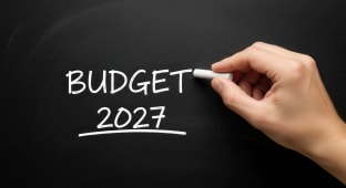 Quelqu'un &eacute;crit &agrave; la main budget 2027 sur un tableau noir.