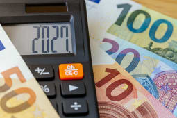 2027 inscrit sur l'&eacute;cran d'une calculatrice, avec des billets de banque. 