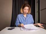 Une femme regarde un document l'air surpris.