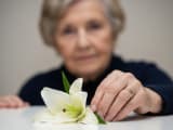 Femme &acirc;g&eacute;e en deuil, d&eacute;posant un lys blanc, exprimant sa tristesse pour les fun&eacute;railles et le souvenir.