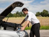 Un homme devant sa voiture en panne.