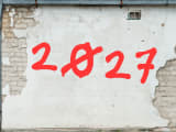 Le nombre 2027 peint en rouge sur un mur abîmé.