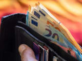Portefeuille noir rempli de billets en euros et de cartes de cr&eacute;dit tenu &agrave; la main
