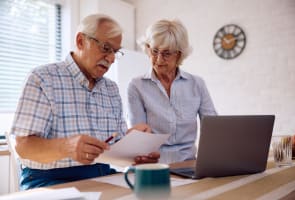 Deux personnes ges regardent un document et un ordinateur.