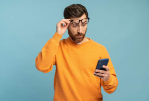 Un homme regarde son t�l�phone l'air surpris.