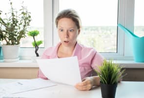 Une femme choqu�e regardant une lettre, examinant des papiers avec des documents bancaires.