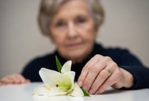 Femme �g�e en deuil, d�posant un lys blanc, exprimant sa tristesse pour les fun�railles et le souvenir.