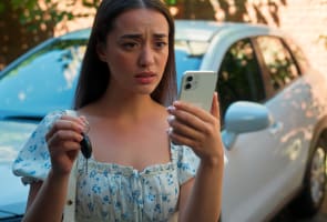 Une femme tenant des cl�s de voiture, regardant son t�l�phone l'air inquiet.