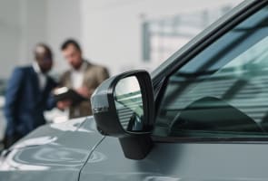 Un concessionnaire automobile conseille un client sur l'achat ou la location d'une nouvelle voiture.