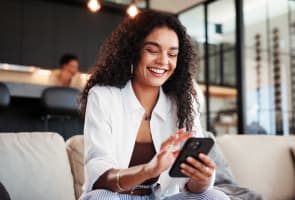 T�l�phone portable, sourire, femme sur le canap� � la maison