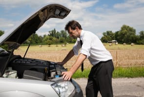 Un homme devant sa voiture en panne.