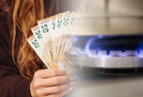 Une femme tenant des billets d'euro pr�s de la flamme d'une cuisini�re � gaz.