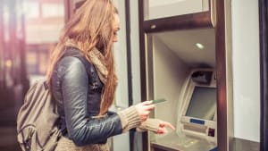 Jeune femme retirant de l'argent à un distributeur