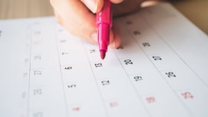 Main avec stylo écrivant sur un calendrier 