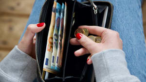 Une jeune femme compte son argent dans son porte-monnaie