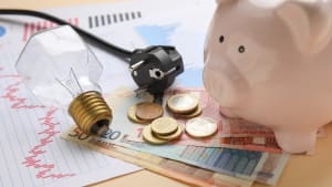 Une ampoule, de l'argent et un document symbolisant des variations de prix.