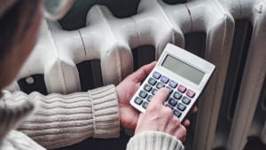 Quelqu'un tient une calculatrice  ct d'un radiateur.