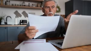 Un homme l'air choqué devant son ordinateur.