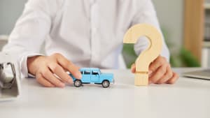 Quelqu'un tient une voiture miniature et un point d'interrogation.