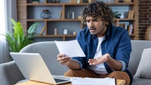 Un homme regarde son ordinateur en s'interrogeant.