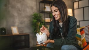 Une femme met de l'argent dans une tirelire.