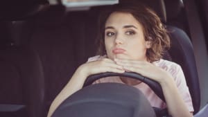 Une jeune femme au volant d'une voiture.