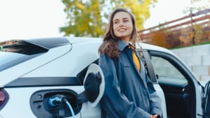 Jeune femme attendant que sa voiture électrique se charge chez elle