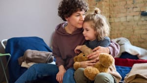 Femme et fille clinant avec un ours en peluche.