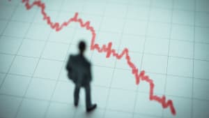 Homme observant une courbe descendante rouge sur graphique.