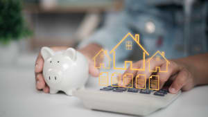 Personne tenant une tirelire et calculatrice, hologramme immobilier.