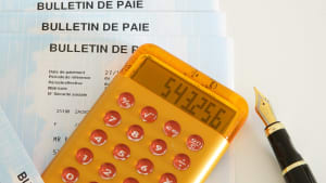 Calculatrice sur bulletins de paie avec stylo.