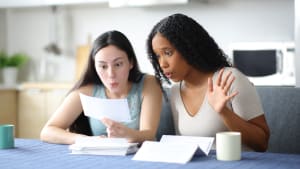 Femmes interraciales surprises vérifiant le relevé bancaire