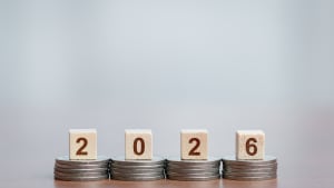 Des pièces empilées soutenant des blocs de bois montrant '2026', concept de croissance financière et de planification future