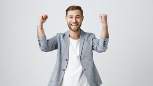 Heureux homme chanceux et ravi avec de la barbe dans des vtements  la mode, il serre les poings, se rjouit de son triomphe au travail, heureux de recevoir des bnfices levs, a sa propre entreprise prospre. Beau gars qui atteint ses objectifs.