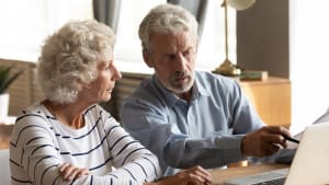 Un couple g utilisant un ordinateur portable.