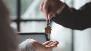 Remise de clés de maison entre deux personnes indoors.