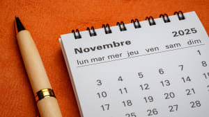 Calendrier de novembre 2025 avec un stylo sur fond orange.
