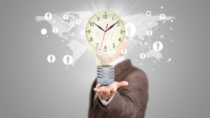 Un homme d'affaires en costume tient une ampoule avec une horloge